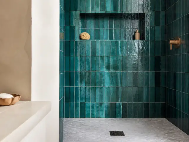 Mur de douche à l’italienne carrelé de zellige bleu canard aux reflets irréguliers, avec une niche et une colonne de douche