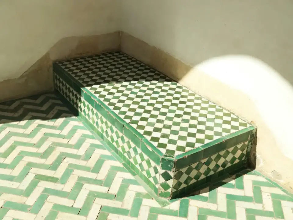 Banc carrelé de zellige vert et blanc dans un coin baigné de soleil