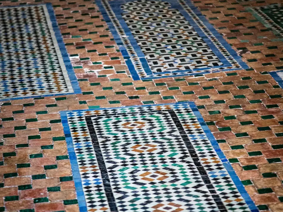 Tapis de zellige à motifs encadrés de bleu posés sur un sol de briques