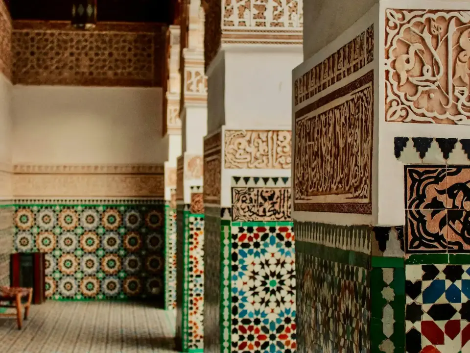 Mur de zellige géométrique bleu, vert et blanc photographié de face dans une cour ancienne