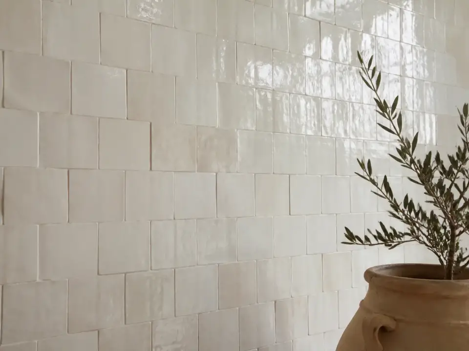 Mur de zellige blanc posé bord à bord, carreaux irréguliers presque jointifs et reflets inégaux de l’émail